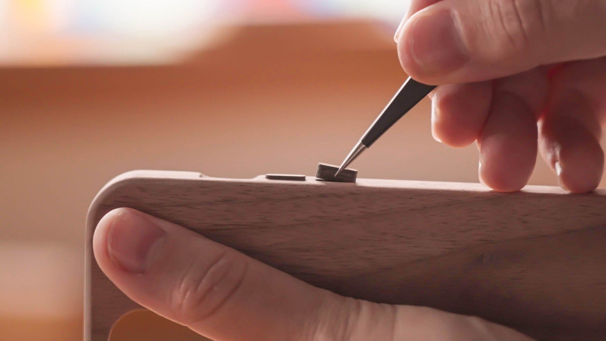 adding a wood button to a wood phone case with tweasers