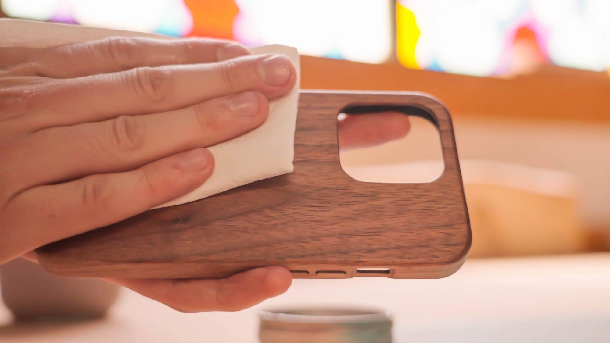 applying natural oil finish to a wooden iphone case by hand with a soft cloth