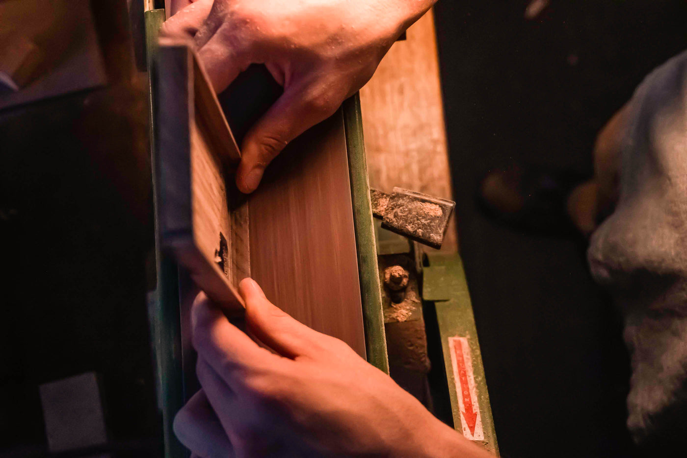 hand sanding a wooden phone case on a vintage belt sander