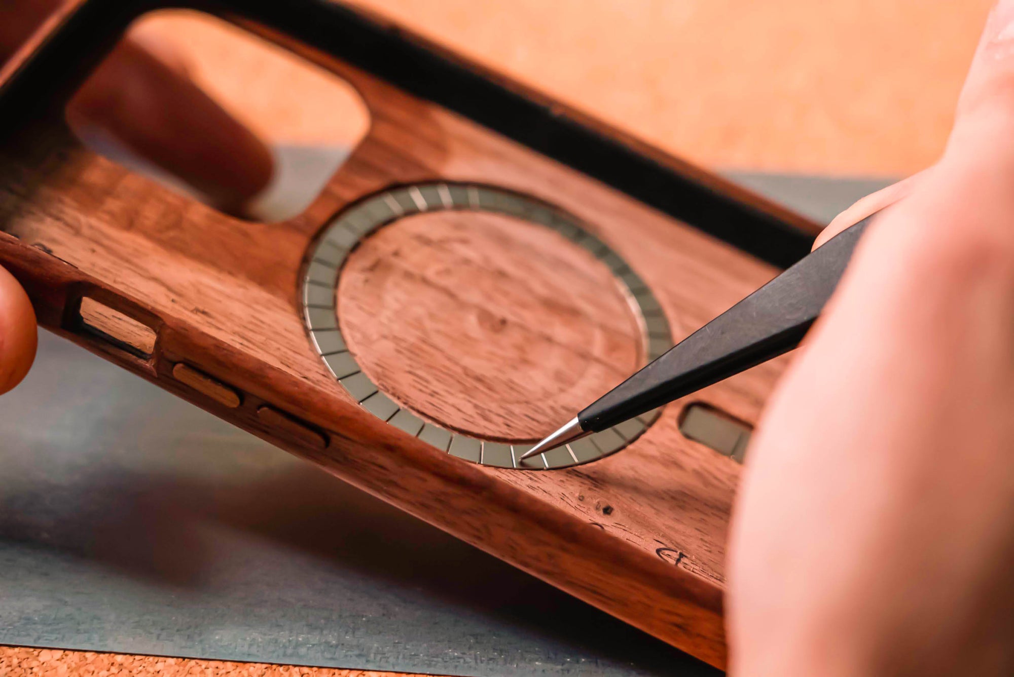 using tweezers to add MagSafe magnets to a wooden iphone case 